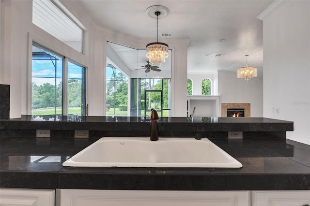 kitchen with an inviting chandelier, sink, white cabinetry, and decorative light fixtures