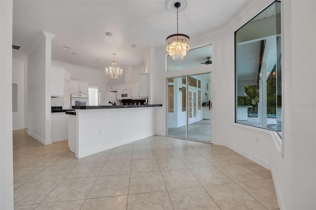 kitchen featuring ceiling fan with notable chandelier, white appliances, pendant lighting, kitchen peninsula, and white cabinetry