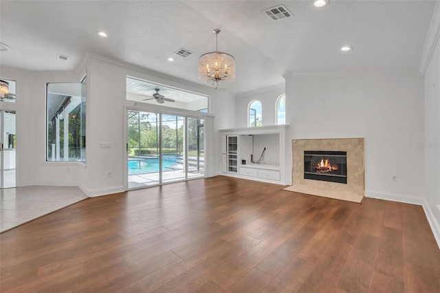 unfurnished living room featuring a fireplace, ceiling fan with notable chandelier, crown molding, a textured ceiling, and hardwood / wood-style flooring