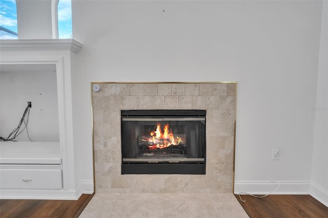 interior details featuring a tiled fireplace and hardwood / wood-style flooring