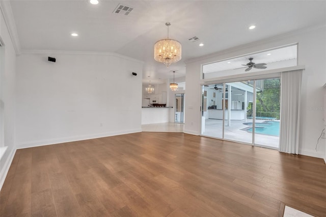 empty room featuring lofted ceiling, ceiling fan with notable chandelier, wood-type flooring, and ornamental molding