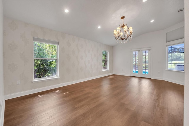 empty room featuring lofted ceiling, a chandelier, dark hardwood / wood-style flooring, and french doors