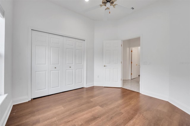 unfurnished bedroom featuring light hardwood / wood-style flooring, ceiling fan, and a closet