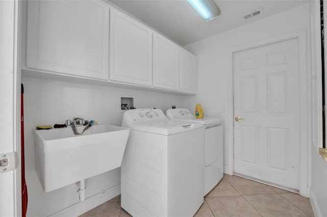 laundry room with light tile patterned floors, cabinets, washer and dryer, and sink