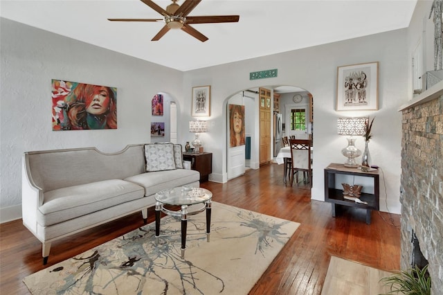 living room with ceiling fan and dark hardwood / wood-style flooring