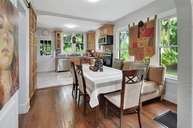 dining area with plenty of natural light, a barn door, light hardwood / wood-style flooring, and sink