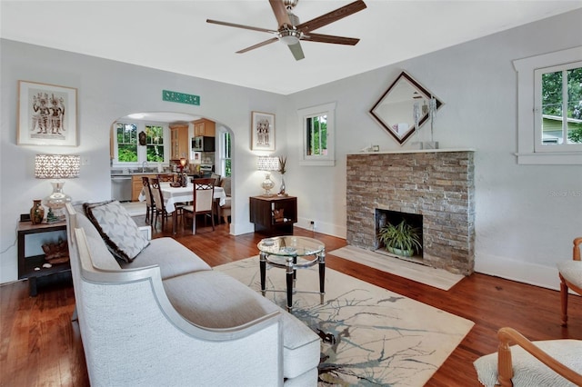 living room featuring dark wood-type flooring, plenty of natural light, and ceiling fan