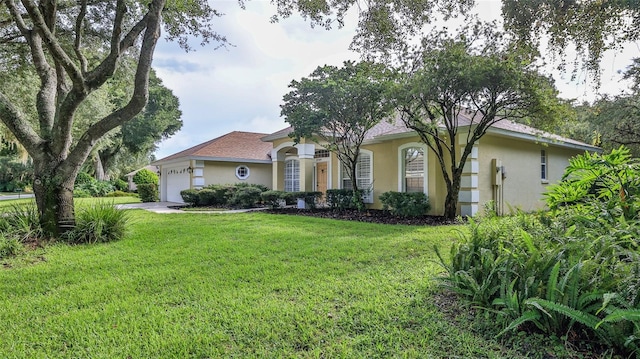 view of front of home with stucco siding, a front lawn, and an attached garage