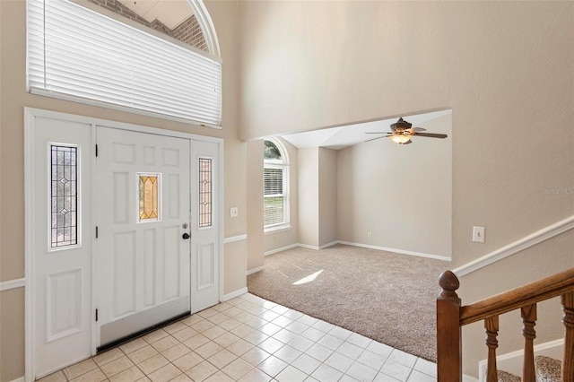 carpeted foyer entrance with ceiling fan and a towering ceiling