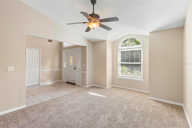 carpeted empty room featuring vaulted ceiling, a textured ceiling, and ceiling fan