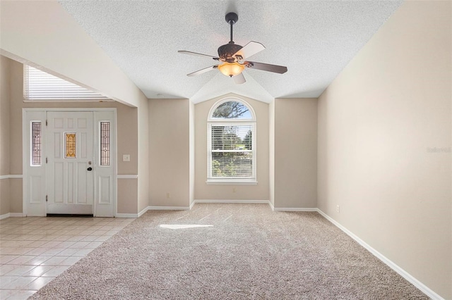 tiled entrance foyer with lofted ceiling, ceiling fan, and a textured ceiling