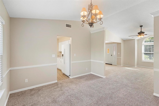 carpeted empty room featuring lofted ceiling, ceiling fan with notable chandelier, and a textured ceiling