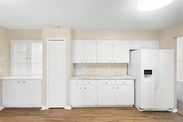 kitchen with light wood-type flooring, white refrigerator with ice dispenser, and white cabinetry