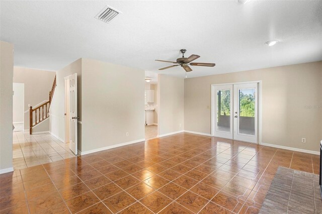 spare room featuring french doors, a textured ceiling, dark tile patterned floors, and ceiling fan