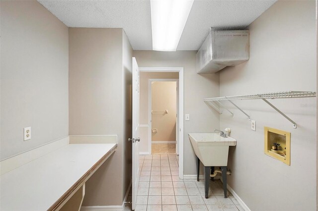 laundry room featuring hookup for a washing machine, light tile patterned floors, and a textured ceiling