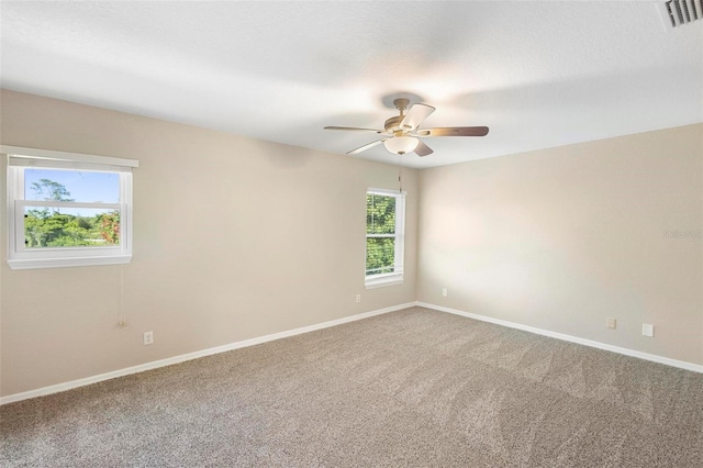 carpeted empty room with ceiling fan and plenty of natural light