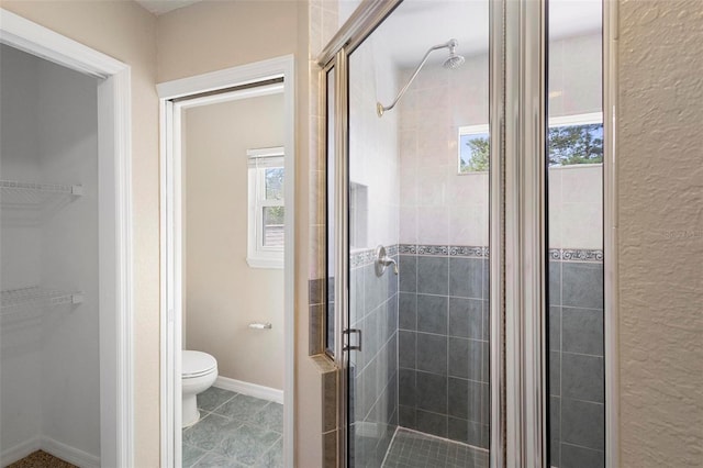 bathroom featuring toilet, walk in shower, and tile patterned flooring