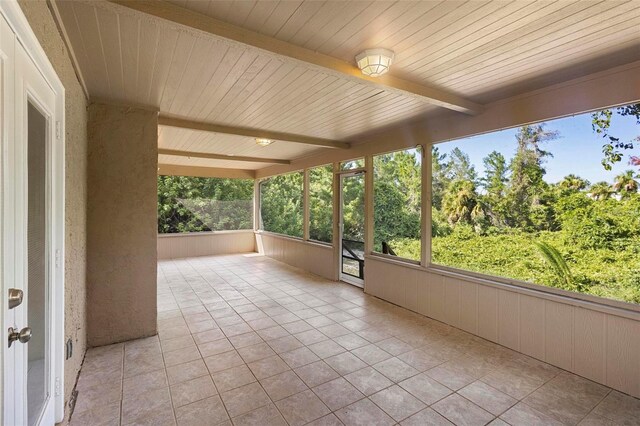 unfurnished sunroom featuring beamed ceiling and wooden ceiling