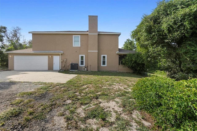 rear view of property with a yard, central AC unit, and a garage