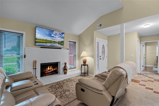 tiled living room with lofted ceiling and a brick fireplace