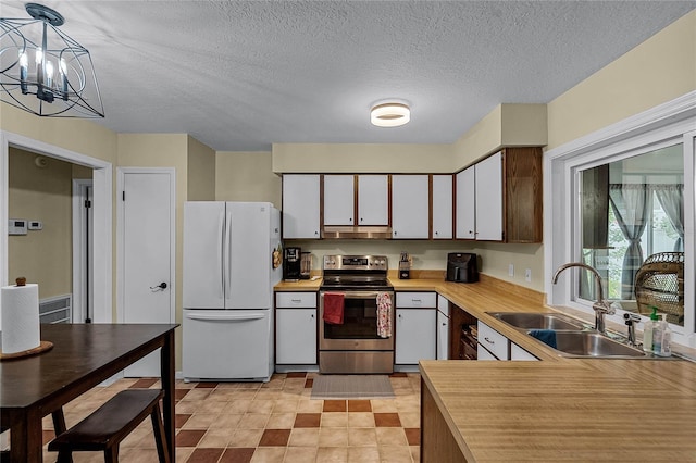 kitchen featuring white fridge, a notable chandelier, hanging light fixtures, sink, and stainless steel range with electric cooktop