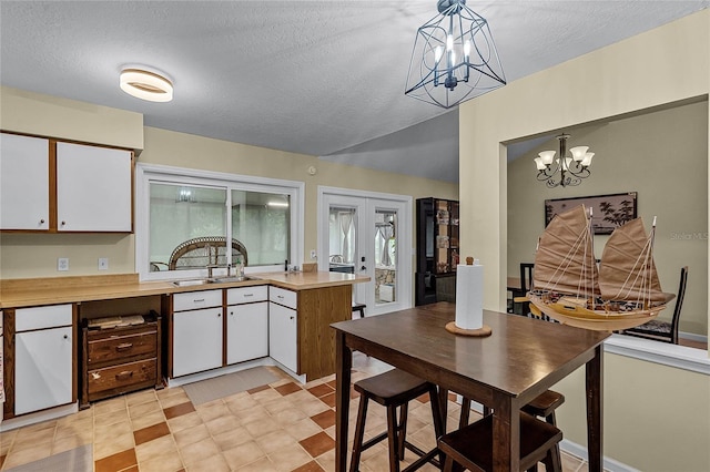 kitchen with pendant lighting, a textured ceiling, and white cabinets