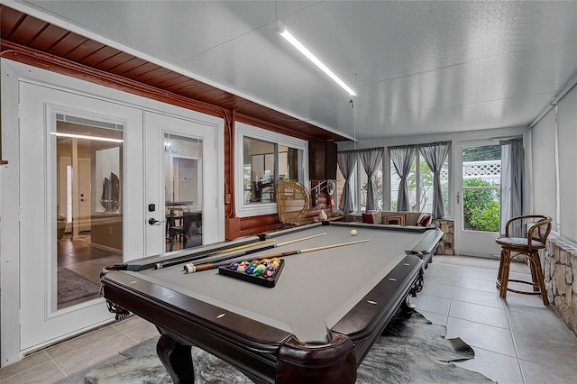 rec room with pool table, light tile patterned floors, wooden walls, and french doors