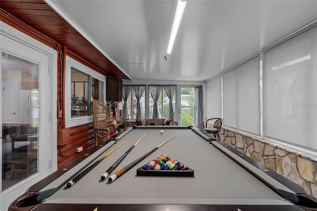 game room featuring a textured ceiling, wood walls, and pool table