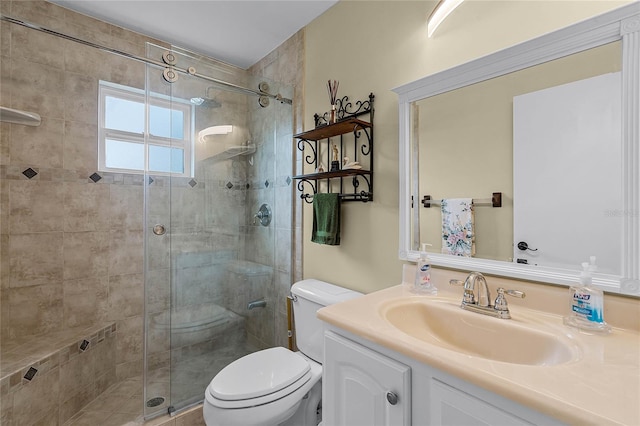 bathroom featuring a shower with shower door, toilet, and vanity