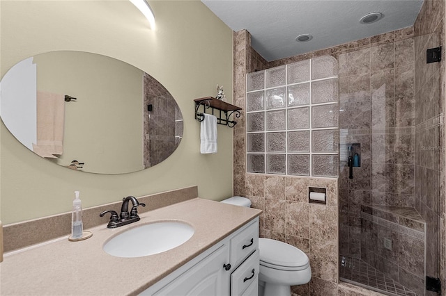 bathroom with vanity, toilet, and a tile shower