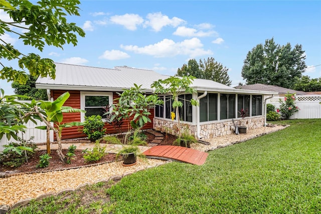 back of property featuring a sunroom and a lawn