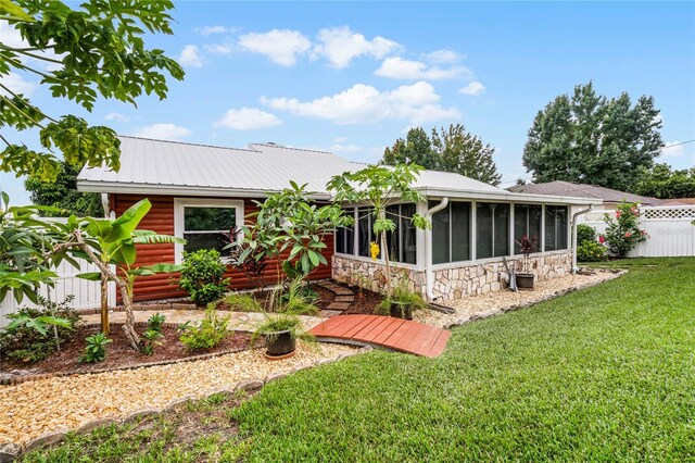 980 Bluebird Ter, Deltona, FL 32725 - rear view of property featuring fence, a yard, stone siding, a sunroom, and metal roof