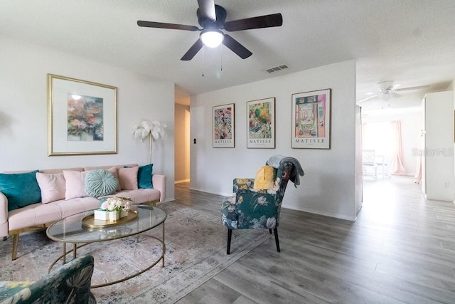 living room featuring a textured ceiling, hardwood / wood-style flooring, and ceiling fan