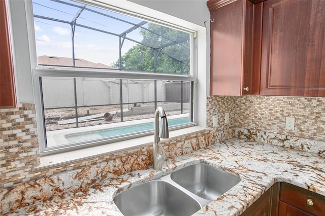 kitchen with light stone counters, sink, tasteful backsplash, and a wealth of natural light