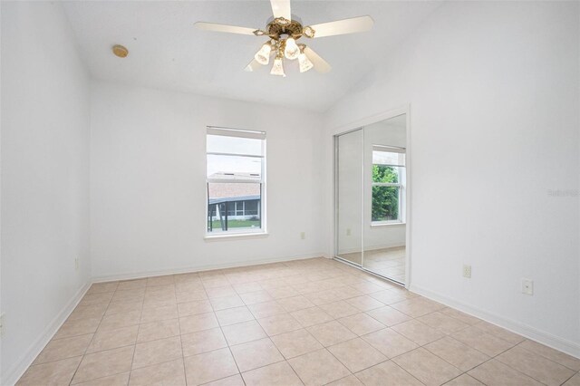 tiled spare room featuring a healthy amount of sunlight, vaulted ceiling, and ceiling fan