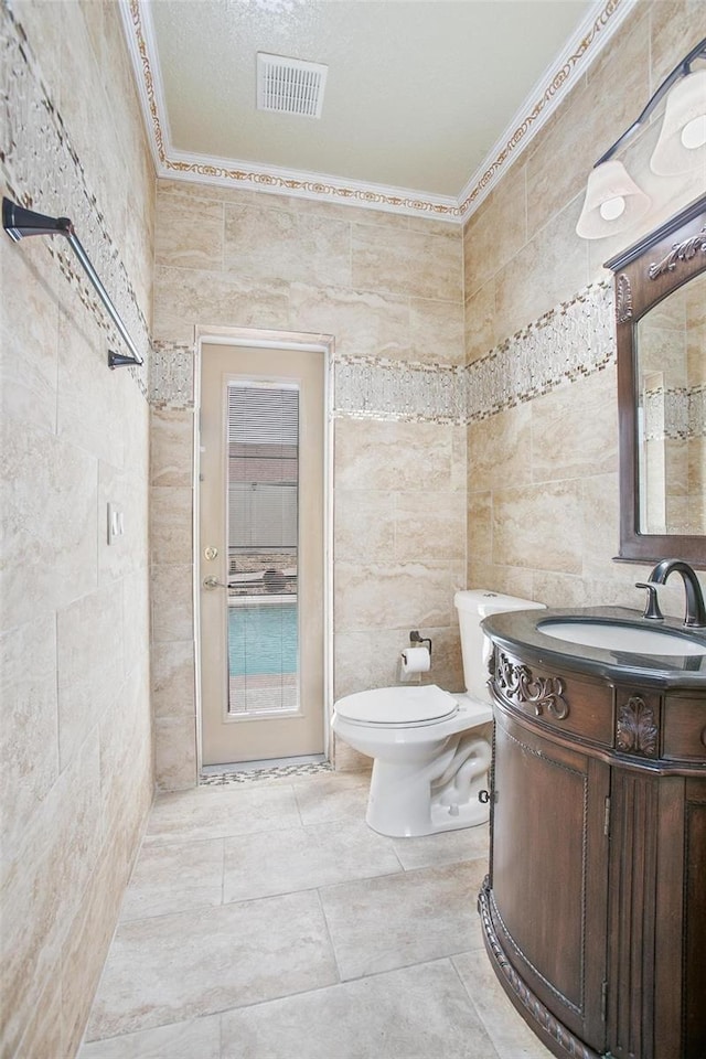 bathroom with vanity, tile walls, toilet, and a textured ceiling