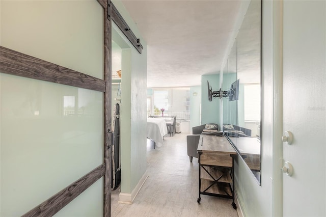 corridor with light hardwood / wood-style floors and a barn door