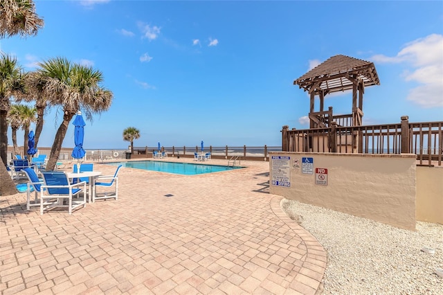 view of pool with a water view and a patio area