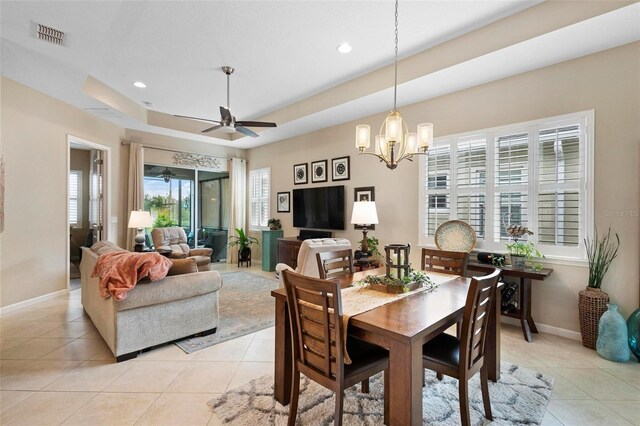 tiled dining space featuring ceiling fan with notable chandelier