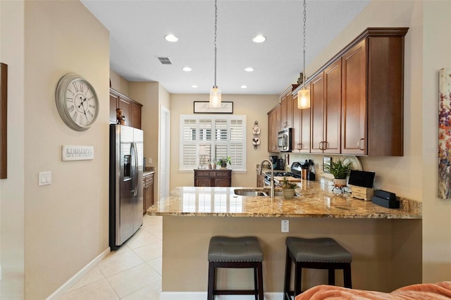 kitchen with light stone countertops, kitchen peninsula, appliances with stainless steel finishes, and decorative light fixtures