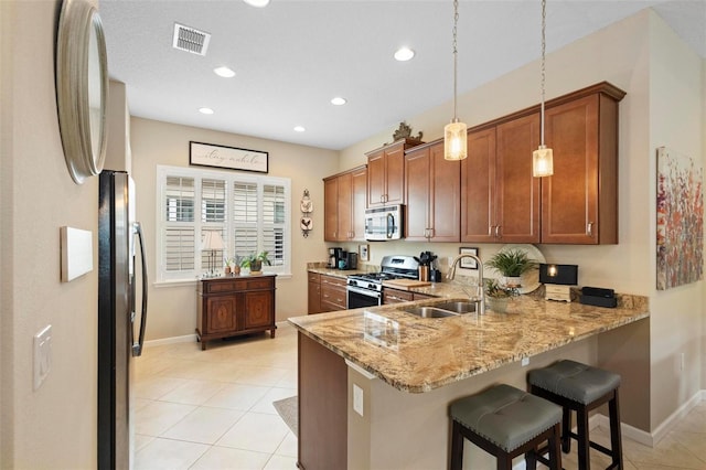 kitchen featuring pendant lighting, sink, kitchen peninsula, stainless steel appliances, and light stone countertops