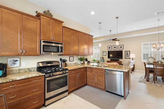 kitchen featuring hanging light fixtures, sink, kitchen peninsula, appliances with stainless steel finishes, and ceiling fan with notable chandelier