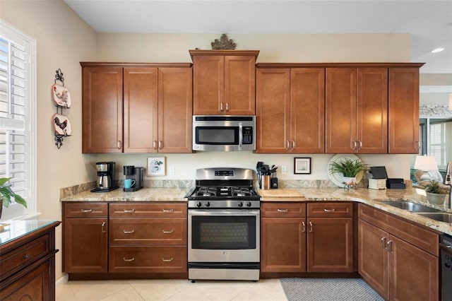 kitchen featuring light stone counters, light tile patterned floors, appliances with stainless steel finishes, and sink