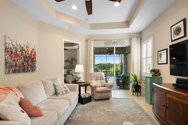 tiled living room featuring a tray ceiling and ceiling fan