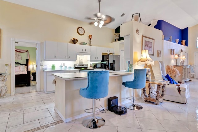 kitchen featuring ceiling fan, kitchen peninsula, white cabinetry, appliances with stainless steel finishes, and a breakfast bar area