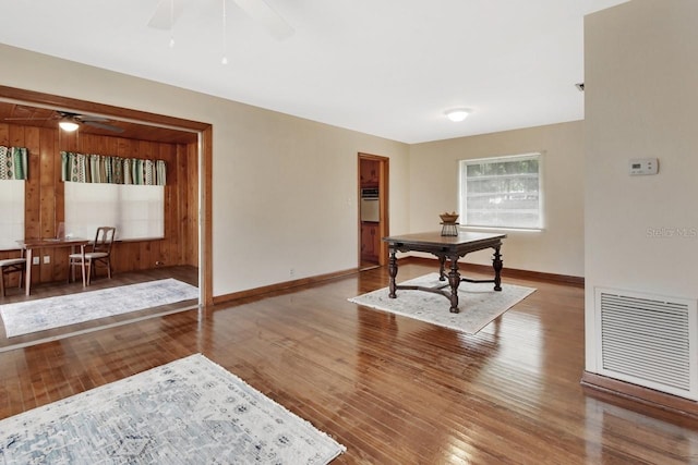 interior space featuring wooden walls, ceiling fan, and hardwood / wood-style flooring