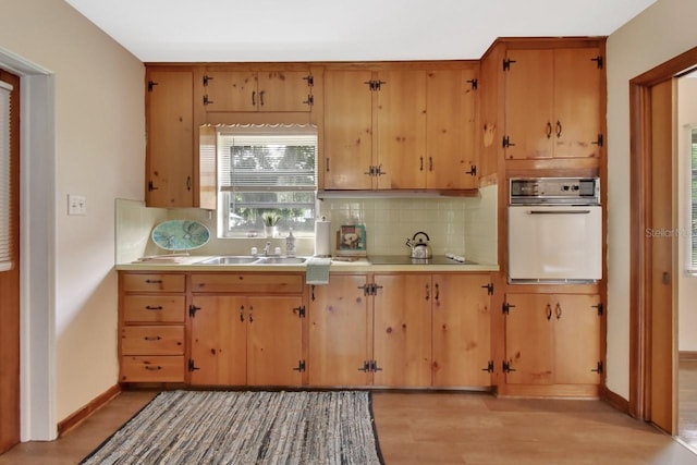 kitchen with black electric cooktop, backsplash, white oven, light wood-type flooring, and sink