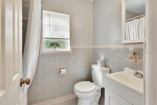 bathroom with vanity, tile walls, and toilet