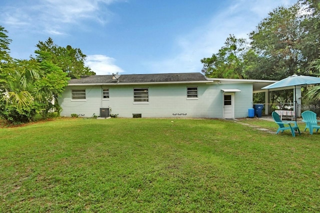 rear view of property featuring a lawn, cooling unit, and a patio area