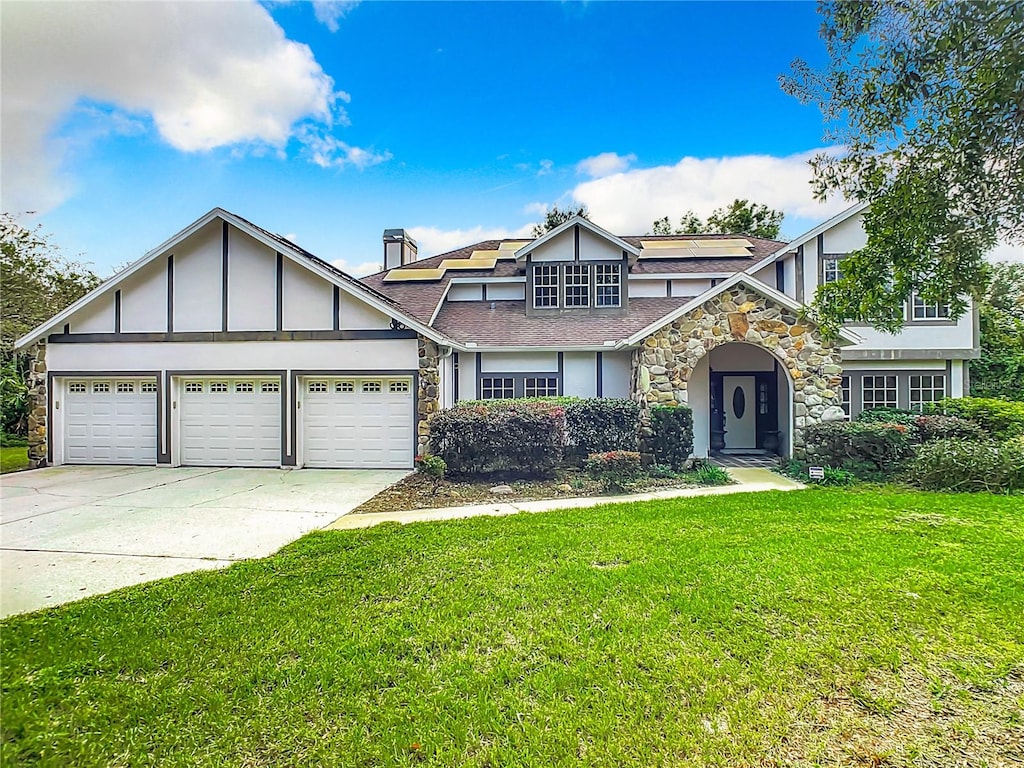 english style home featuring a garage and a front lawn